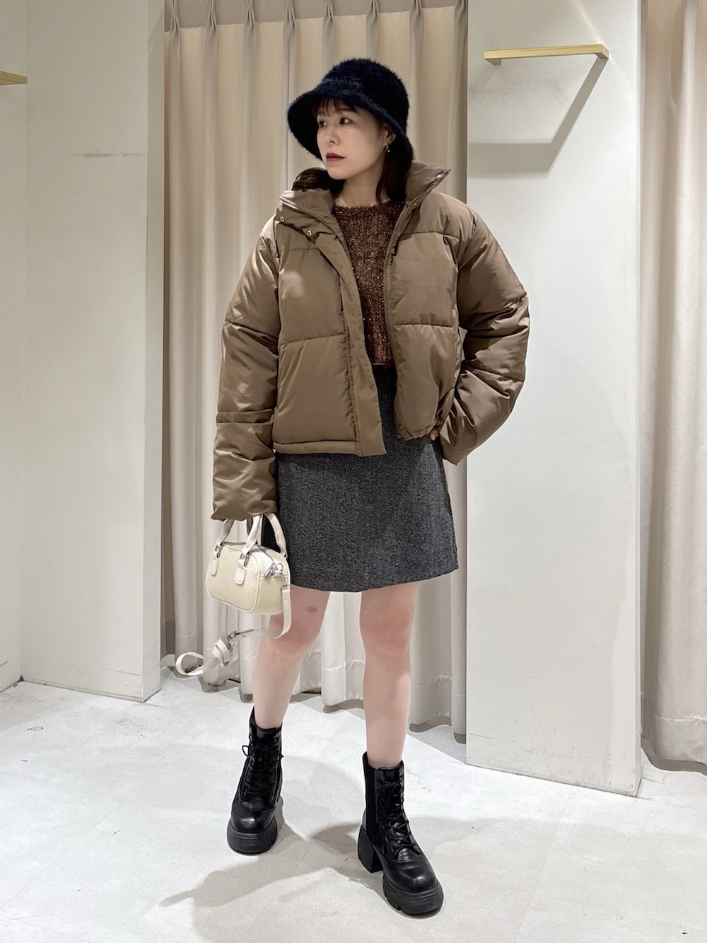ブラウン系のブルゾン、ブラック系のスカート、ホワイト系のボストンバッグを着用したレディースの冬コーディネートの3枚目の写真