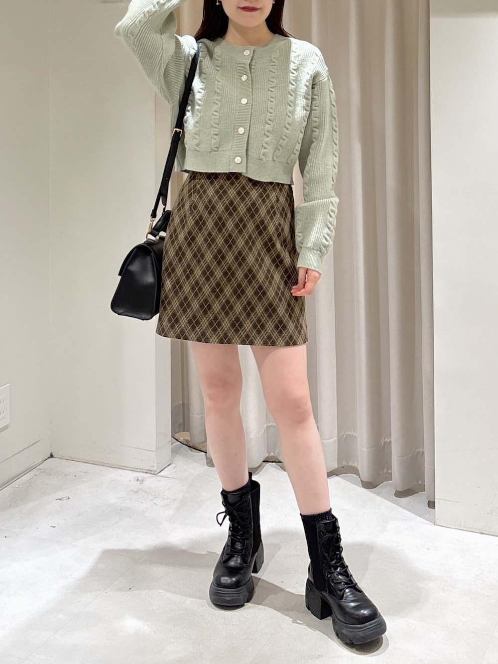 グリーン系のワンピース、ブラック系のブーツ、ブラック系のショルダーバッグを着用したレディースの冬コーディネートの4枚目の写真