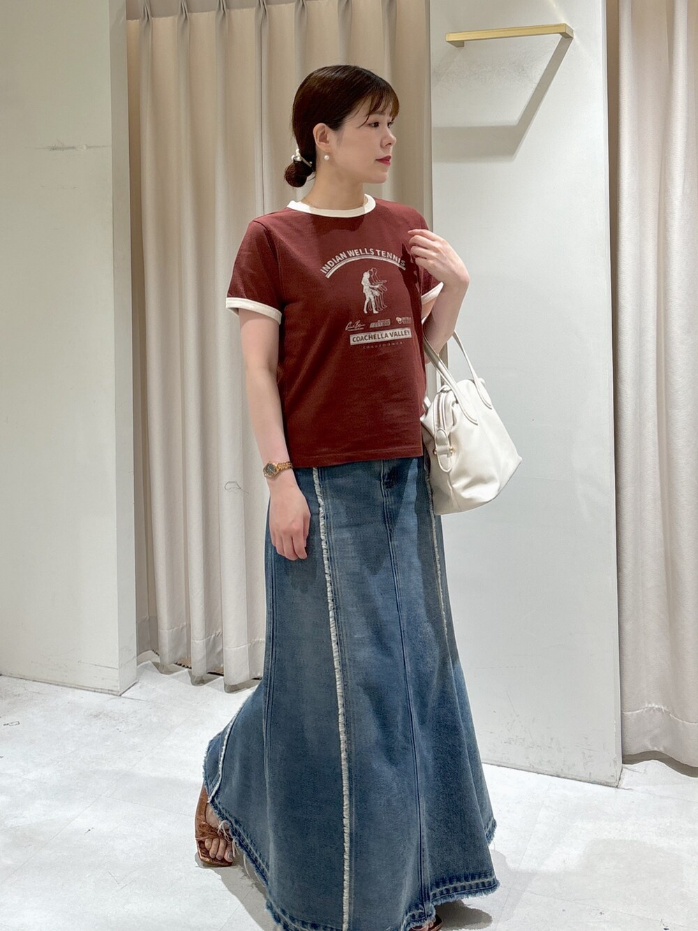 ブラウン系のTシャツ/カットソー、ホワイト系のボストンバッグ、ブルー系のスカートを着用したレディースの夏コーディネートの3枚目の写真