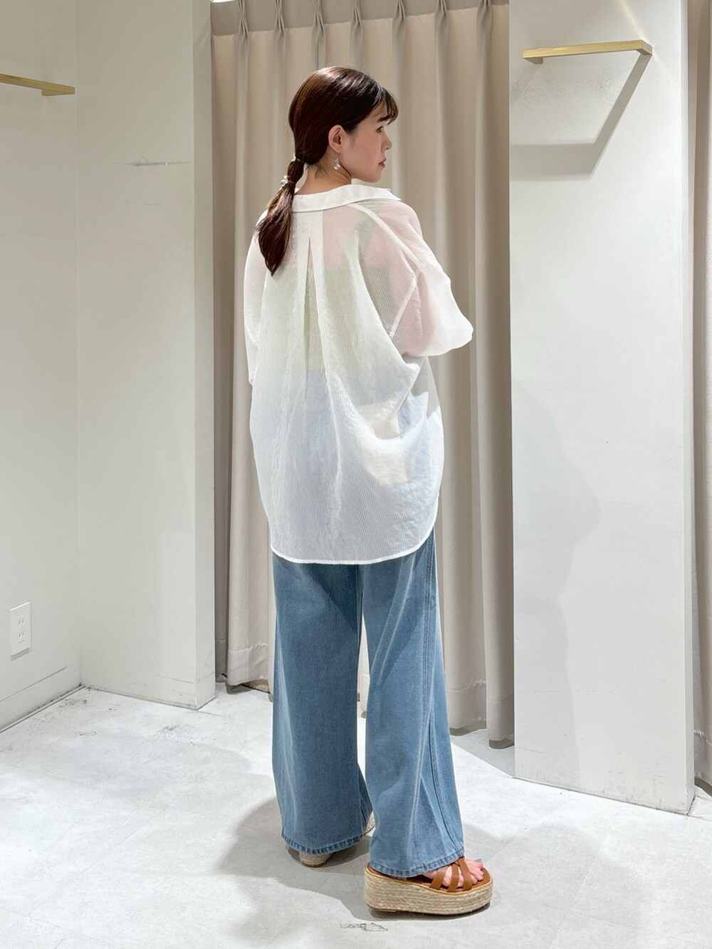 グリーン系のニット/セーター、ブルー系のデニムパンツ、ホワイト系のシャツ/ブラウスを着用したレディースの夏コーディネートの4枚目の写真