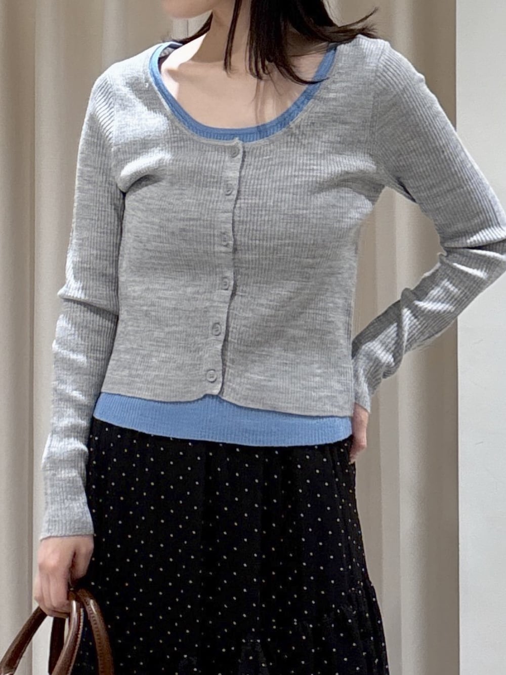 グレー系のニット/セーター、ブラック系のスカート、ブラウン系のハンドバッグを着用したレディースの春コーディネートの2枚目の写真