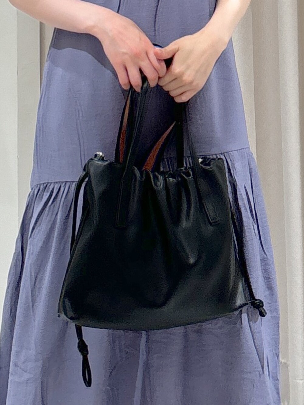 ブルー系のワンピース、ブラック系のハンドバッグ、ゴールド系のサンダルを着用したレディースの夏コーディネートの3枚目の写真