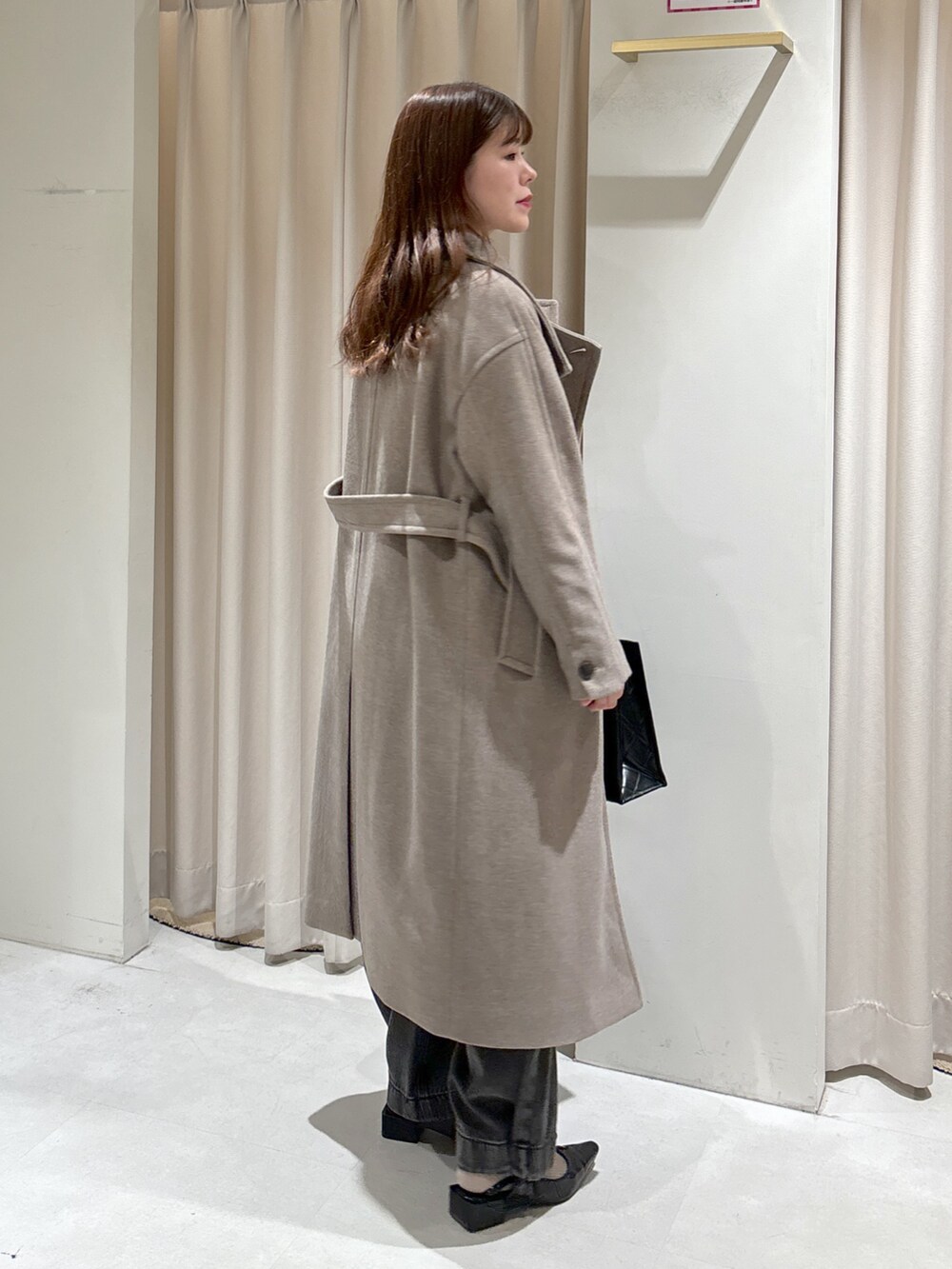 ブラウン系のステンカラーコート、ブラック系のショルダーバッグ、ブラック系のパンプスを着用したレディースの秋コーディネートの3枚目の写真