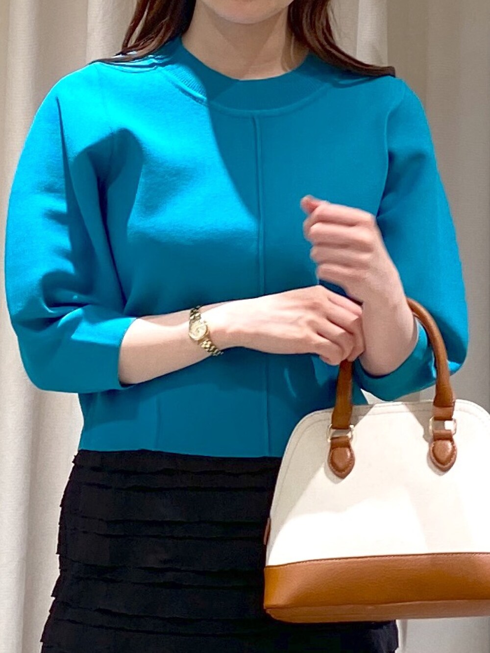 ブラック系のスカート、ブルー系のニット/セーター、ブラウン系のショルダーバッグを着用したレディースの春コーディネートの2枚目の写真