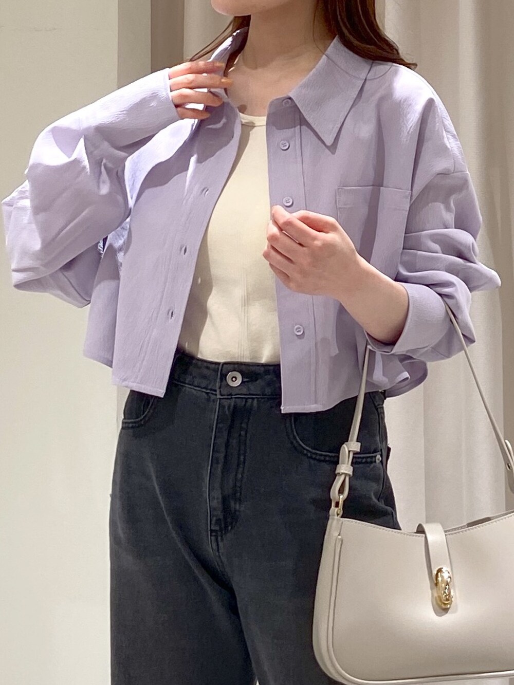 ブラック系のデニムパンツ、ゴールド系のパンプス、グレー系のショルダーバッグを着用したレディースの春コーディネートの2枚目の写真