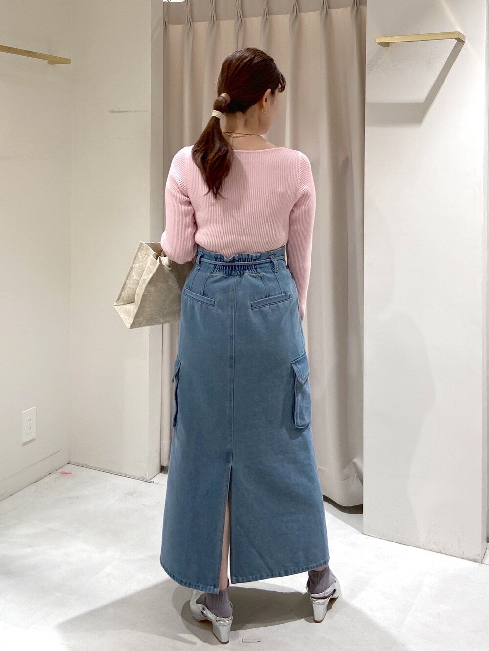 ブルー系のデニムスカート、ホワイト系のトートバッグ、シルバー系のパンプスを着用したレディースの冬コーディネートの2枚目の写真