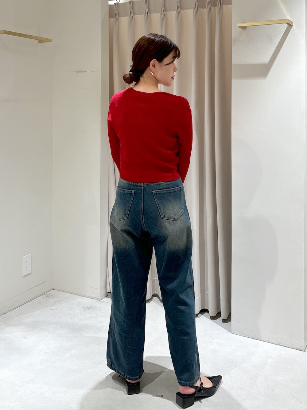 レッド系のニット/セーター、ブルー系のデニムパンツ、ブラック系のショルダーバッグを着用したレディースの秋コーディネートの3枚目の写真