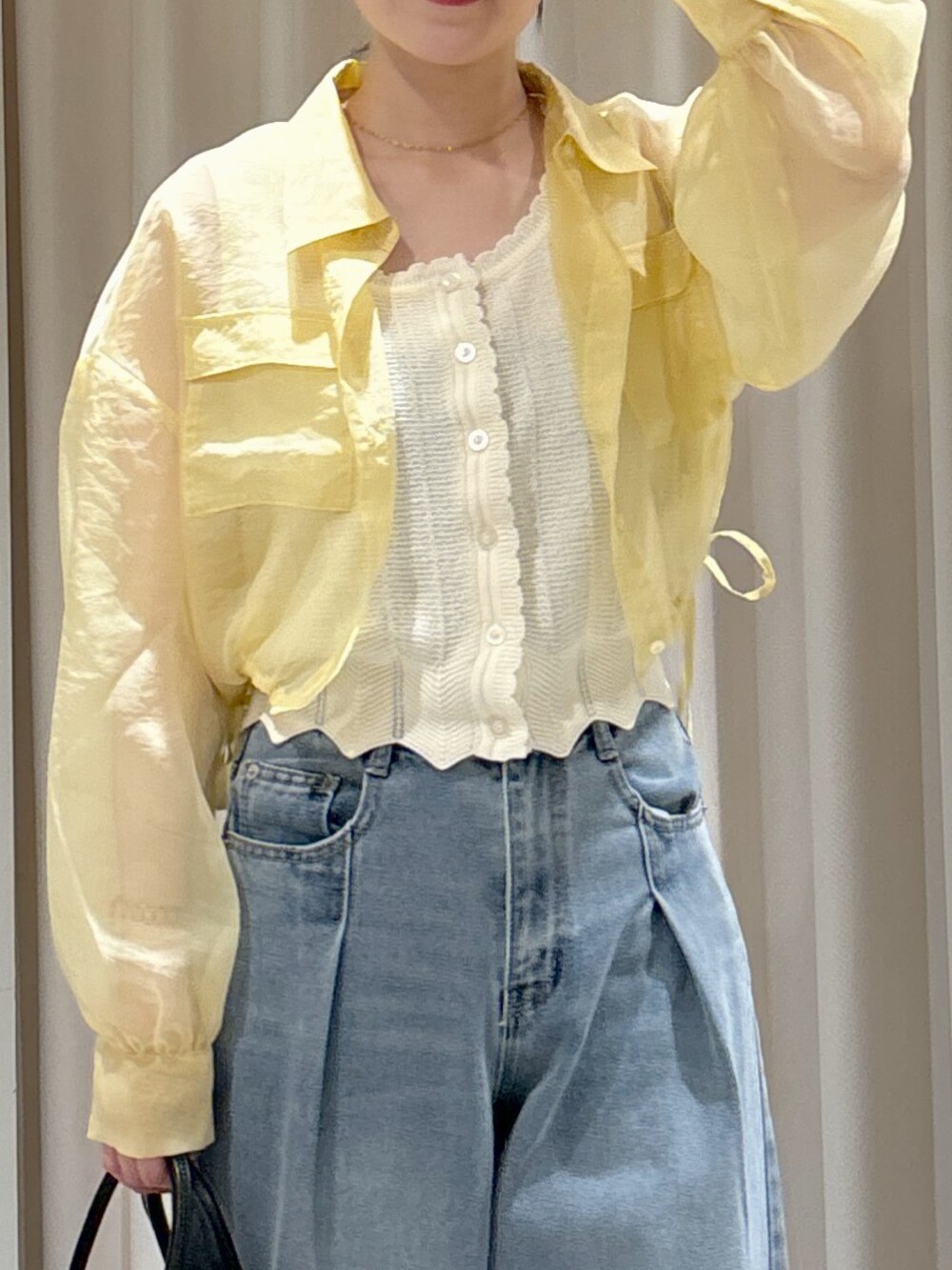 イエロー系のシャツ/ブラウス、ホワイト系のニット/セーター、ブルー系のデニムパンツを着用したレディースの春コーディネートの5枚目の写真