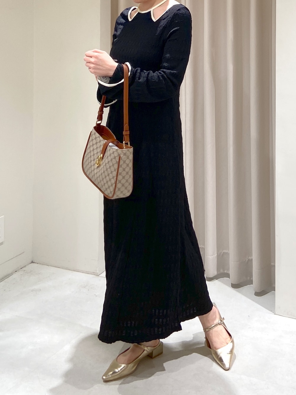 ブラック系のワンピース、ベージュ系のショルダーバッグ、ゴールド系のパンプスを着用したレディースの春コーディネートの3枚目の写真