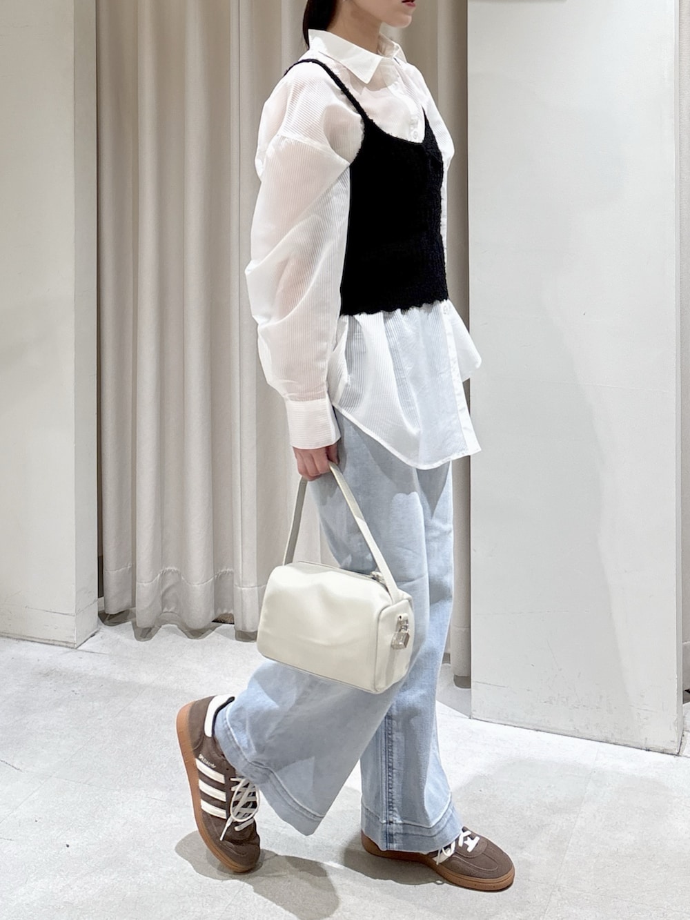 ホワイト系のシャツ/ブラウス、ブラック系のニット/セーター、ブルー系のデニムパンツを着用したレディースの春コーディネートの3枚目の写真