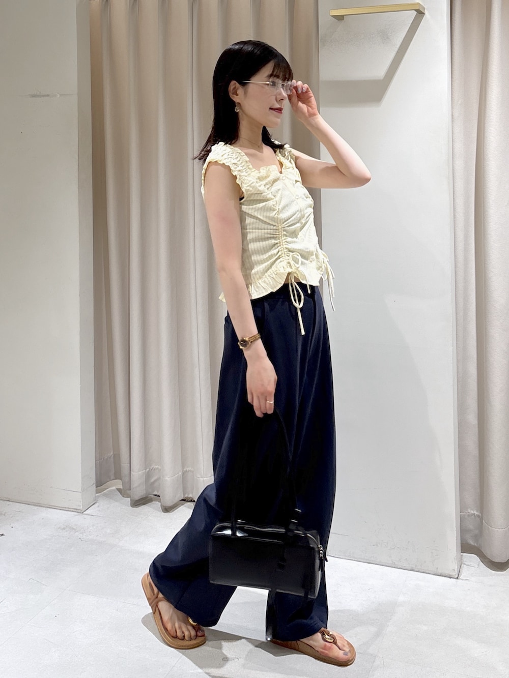 イエロー系のシャツ/ブラウス、ブルー系のその他パンツ、ブラック系のショルダーバッグを着用したレディースの夏コーディネートの2枚目の写真