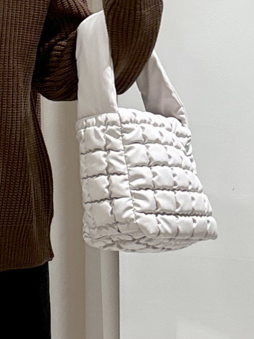 ブラウン系のニット/セーター、ホワイト系のハンドバッグ、ブラック系のスカートを着用したレディースの秋コーディネートの6枚目の写真