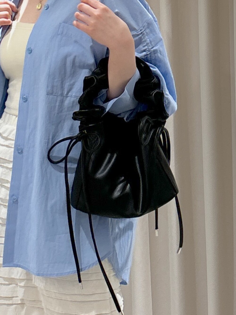 ブラック系のショルダーバッグ、ホワイト系のスカート、ホワイト系のキャミソールを着用したレディースの春コーディネートの6枚目の写真