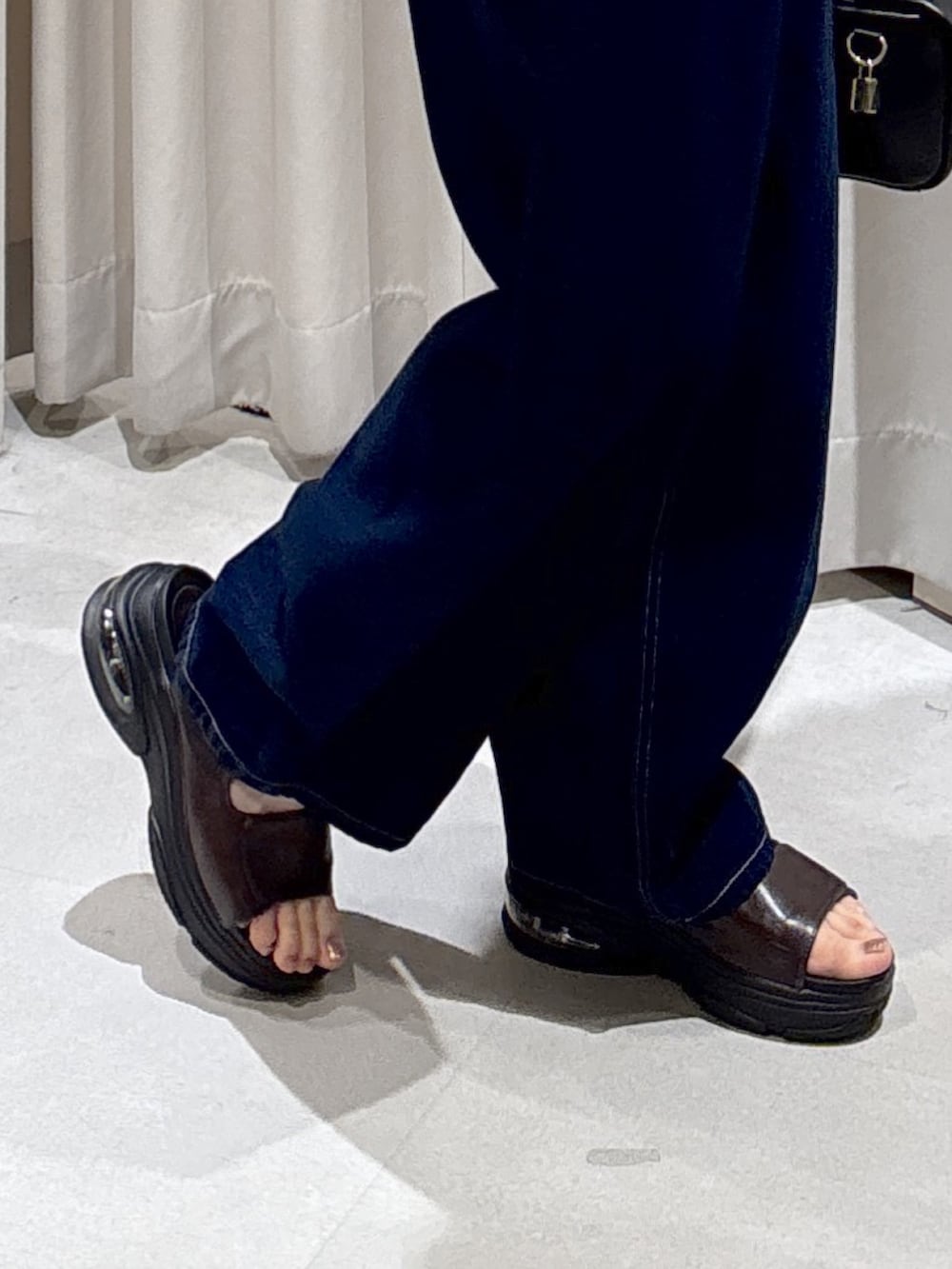 ブルー系のデニムパンツ、ブラック系のハンドバッグ、ブラウン系のサンダルを着用したレディースの夏コーディネートの7枚目の写真