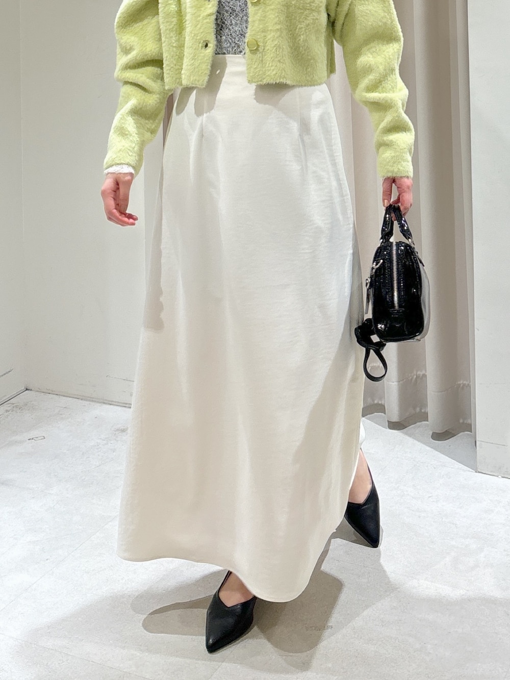 グリーン系のカーディガン/ボレロ、ホワイト系のTシャツ/カットソー、ホワイト系のスカートを着用したレディースの冬コーディネートの3枚目の写真