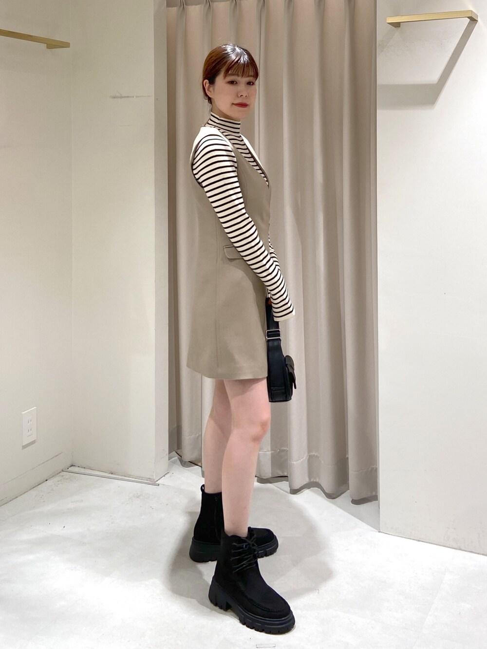 ベージュ系のワンピース、ホワイト系のニット/セーター、ブラック系のショルダーバッグを着用したレディースの冬コーディネートの3枚目の写真