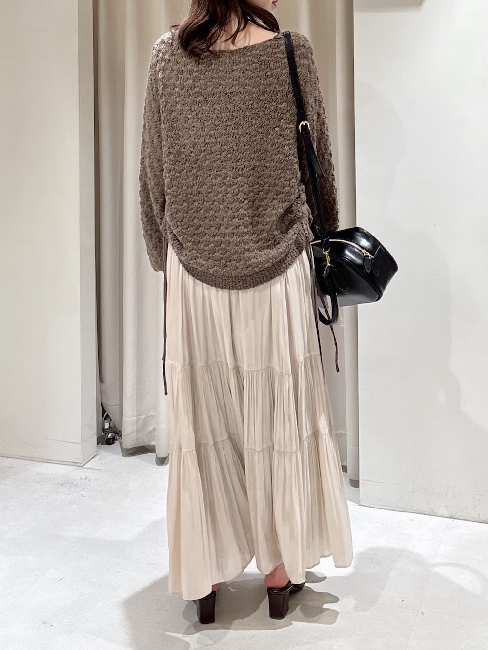 ブラウン系のニット/セーター、ホワイト系のスカート、ブラック系のハンドバッグを着用したレディースの冬コーディネートの5枚目の写真