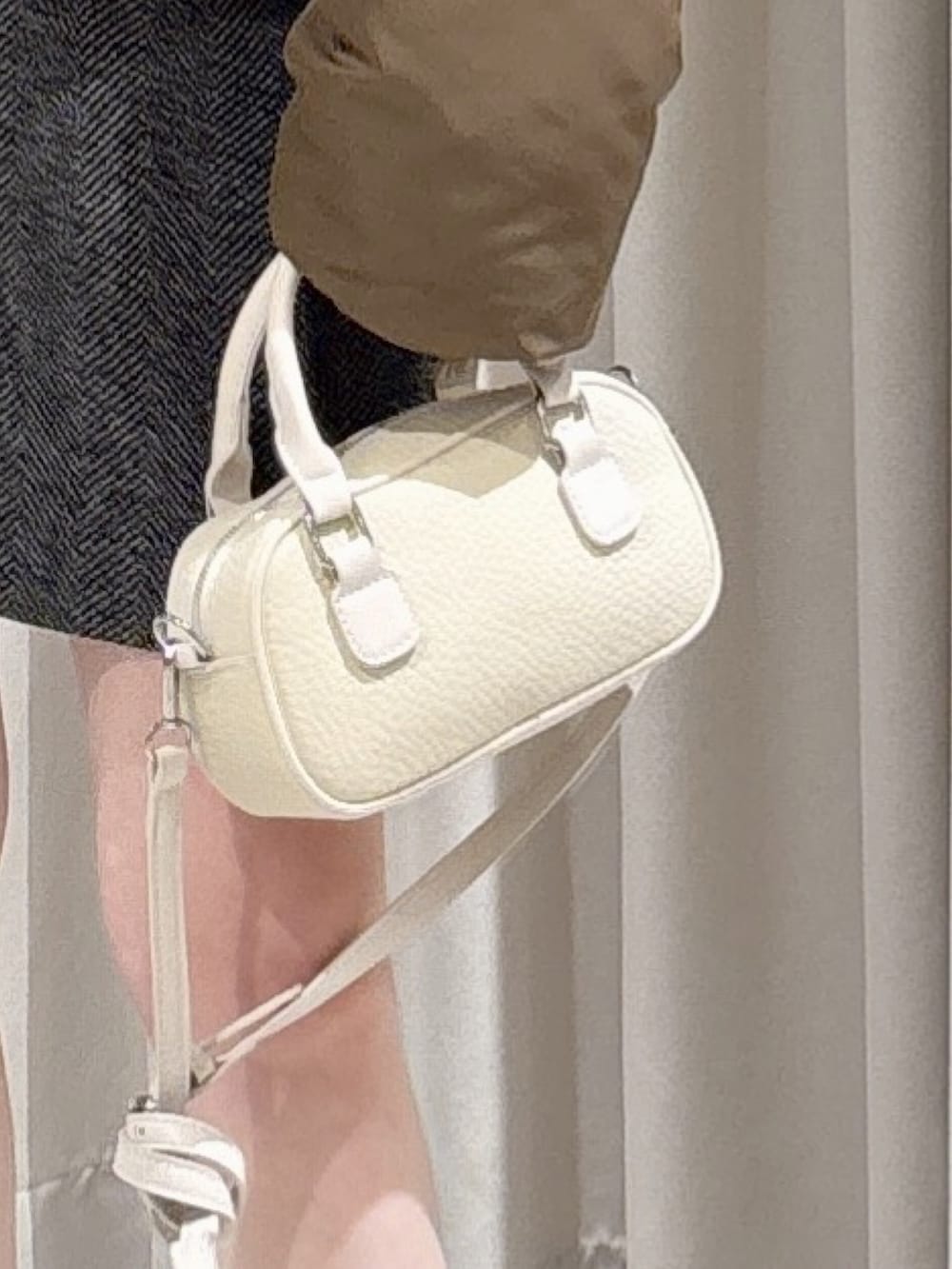 ブラウン系のブルゾン、ブラック系のスカート、ホワイト系のボストンバッグを着用したレディースの冬コーディネートの6枚目の写真