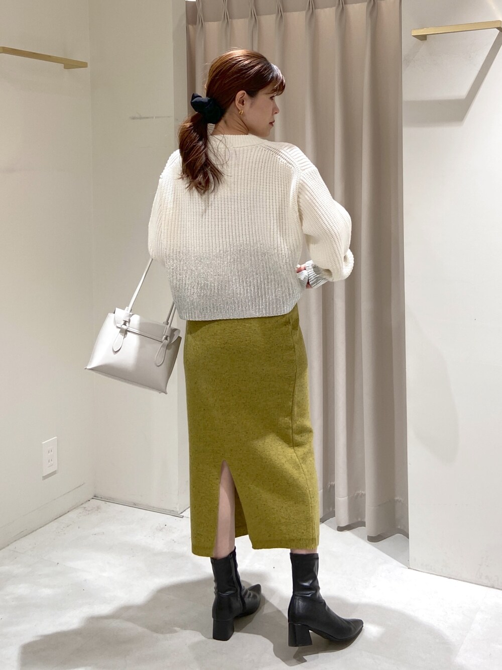 ホワイト系のニット/セーター、グリーン系のスカート、ホワイト系のショルダーバッグを着用したレディースの冬コーディネートの2枚目の写真