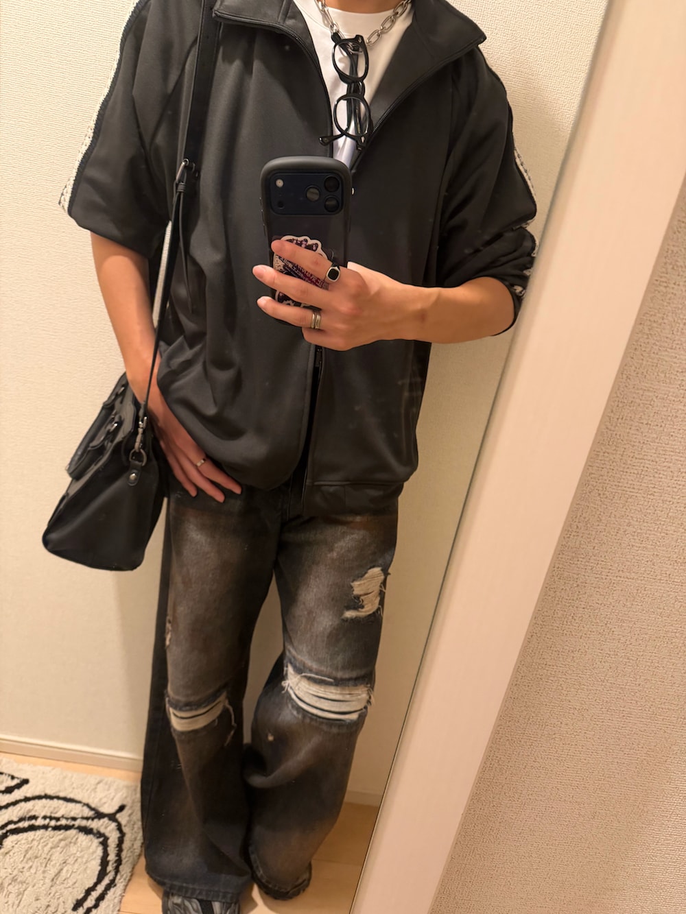 グレー系のジャージ、ブルー系のデニムパンツ、ブラック系のハンドバッグを着用したメンズの秋コーディネートの2枚目の写真