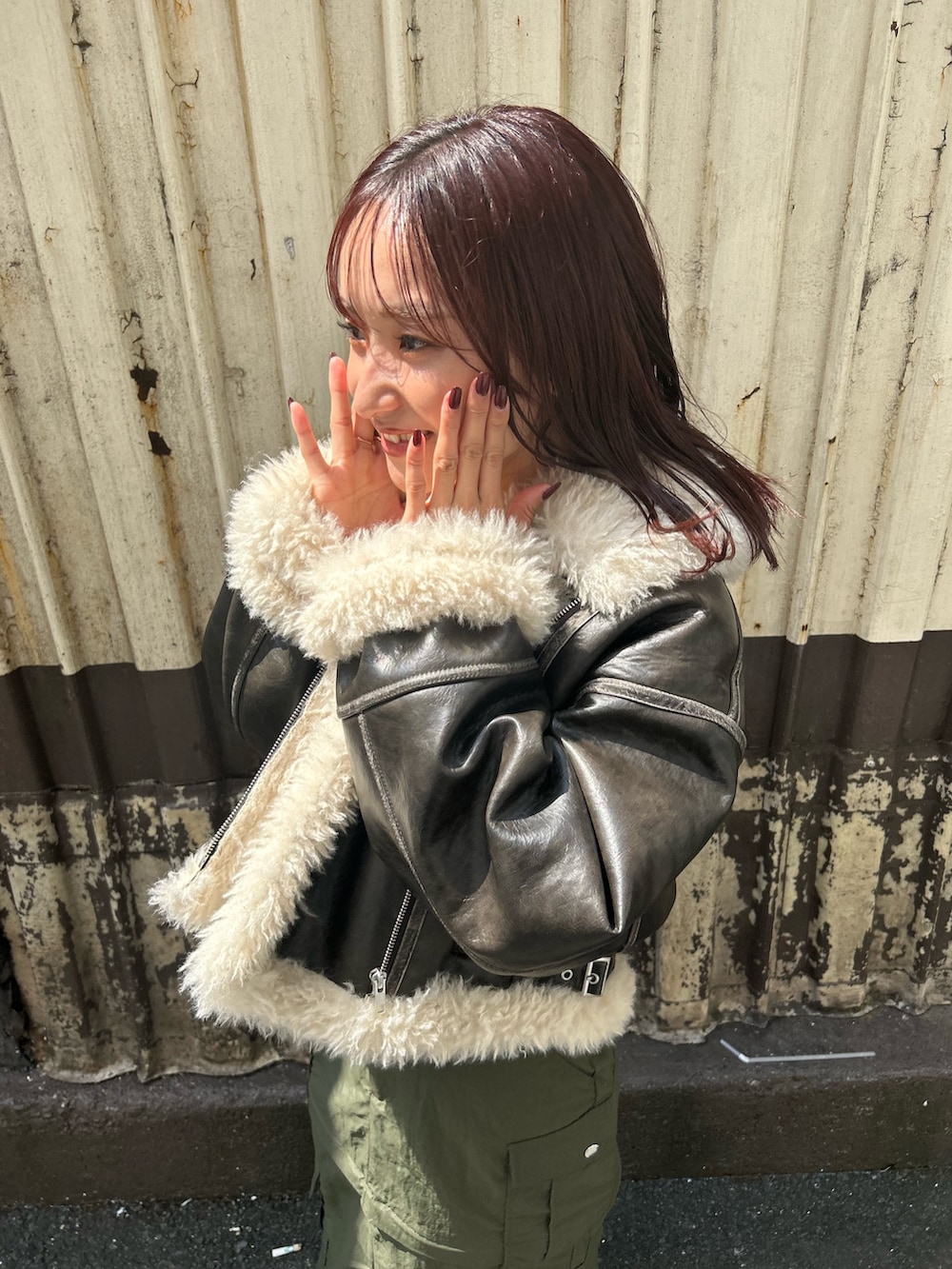 ブラウン系のムートンコート、グレー系のニット/セーター、グリーン系のスカートを着用したレディースの秋コーディネートの5枚目の写真