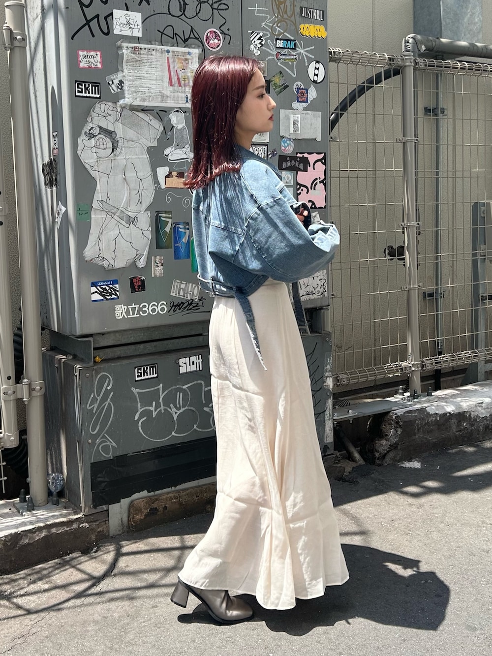 ホワイト系のスカート、ブルー系のデニムジャケット、ブラウン系のブーツを着用したレディースの夏コーディネートの4枚目の写真