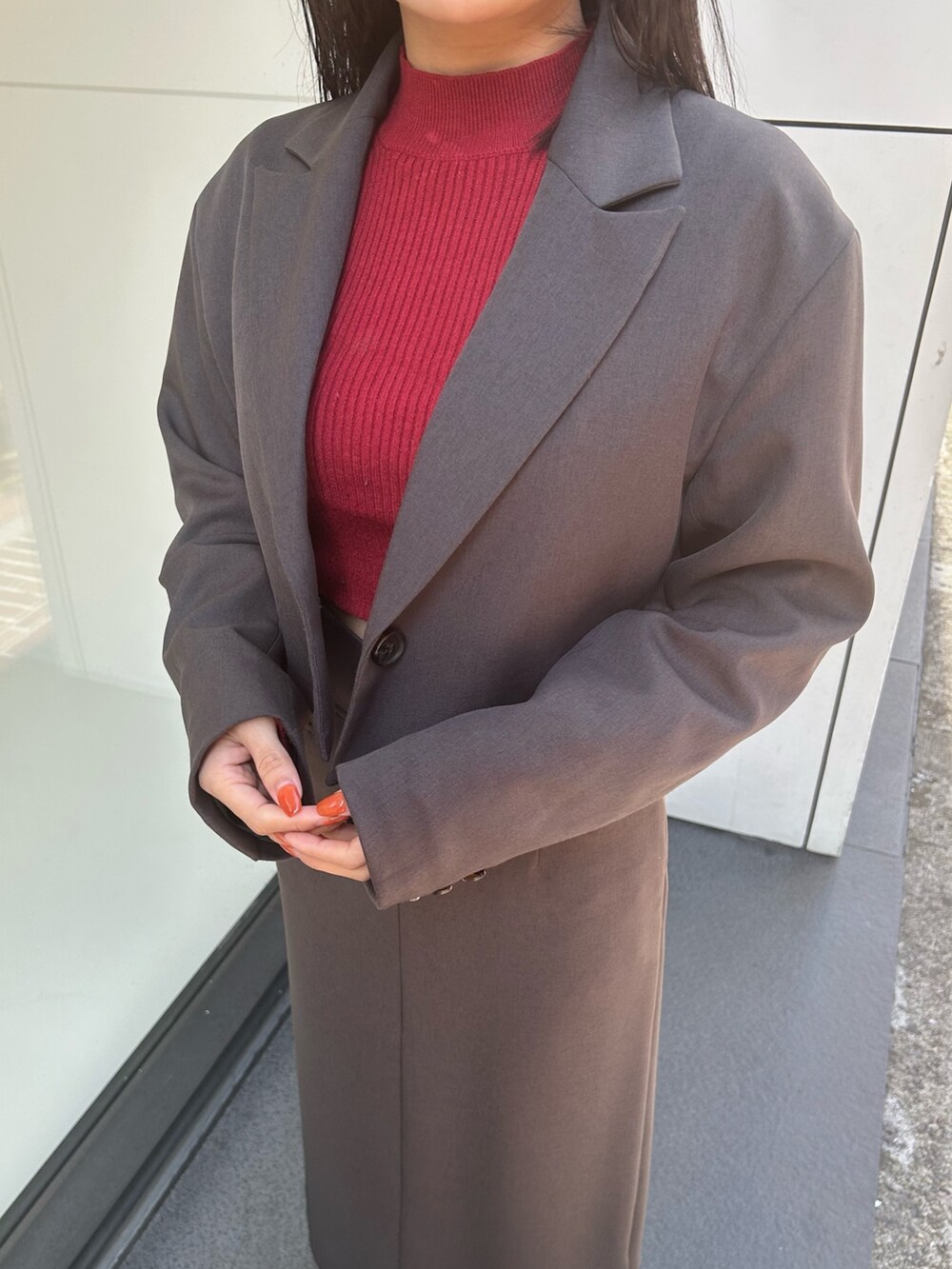 グレー系のテーラードジャケット、グレー系のスカート、ブラック系のブーツを着用したレディースの冬コーディネートの3枚目の写真