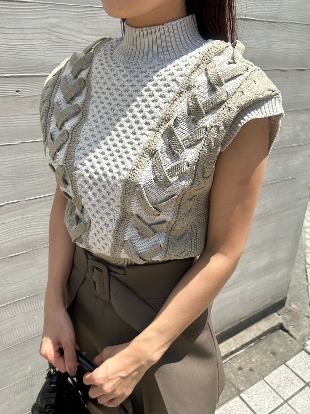 ブラウン系のブーツ、ブラウン系のスラックス、ブラック系のハンドバッグを着用したレディースの夏コーディネートの3枚目の写真