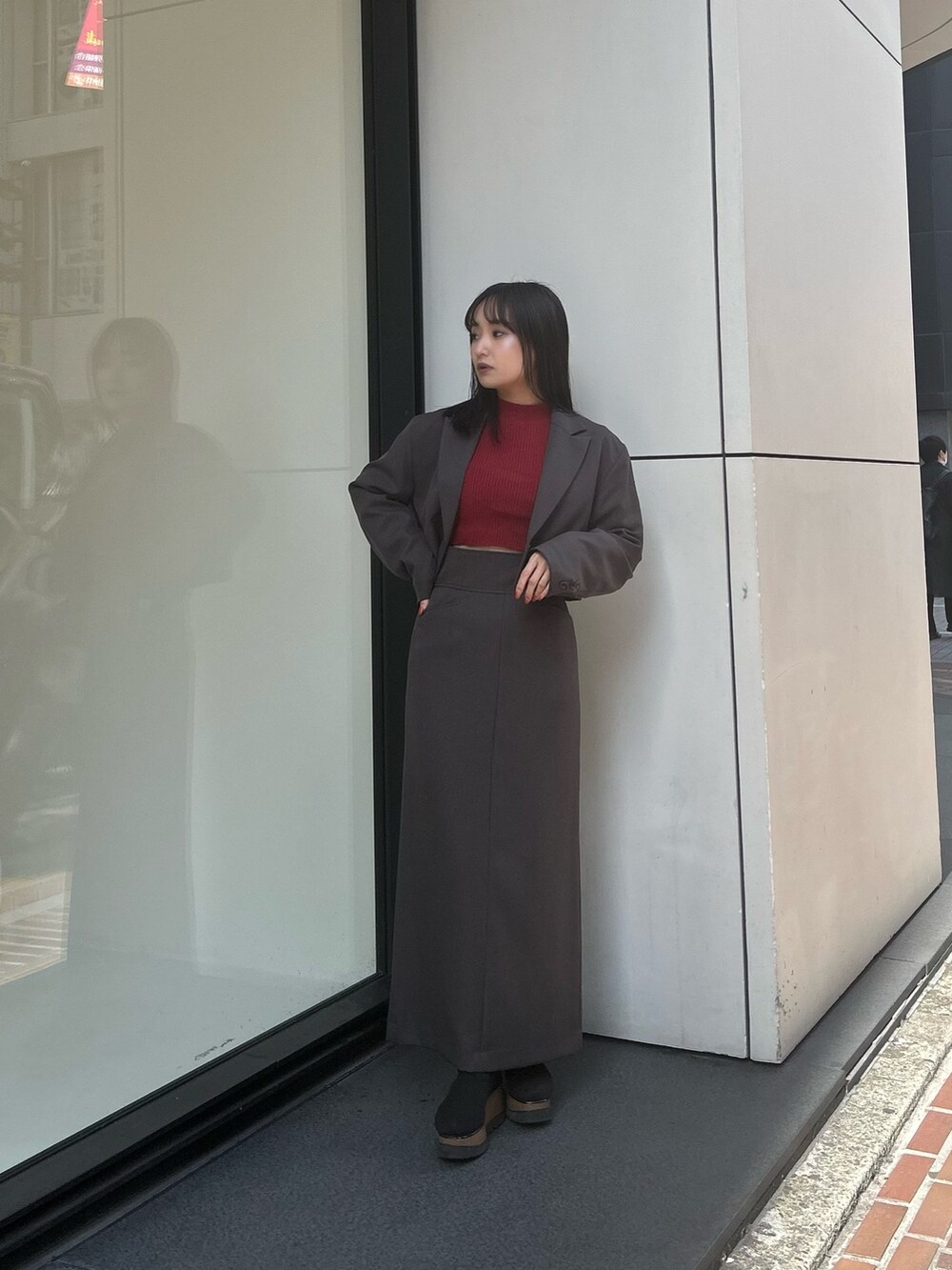 グレー系のテーラードジャケット、グレー系のスカート、ブラック系のブーツを着用したレディースの冬コーディネートの2枚目の写真
