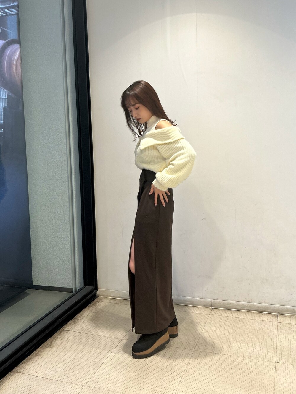 ホワイト系のニット/セーター、ブラック系のブーツ、ブラウン系のスカートを着用したレディースの冬コーディネートの2枚目の写真