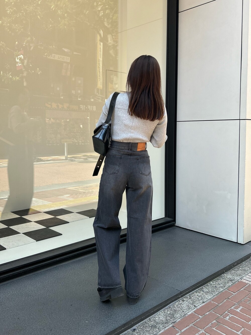 グレー系のTシャツ/カットソー、ブラック系のデニムパンツ、ブラック系のショルダーバッグを着用したレディースの春コーディネートの3枚目の写真