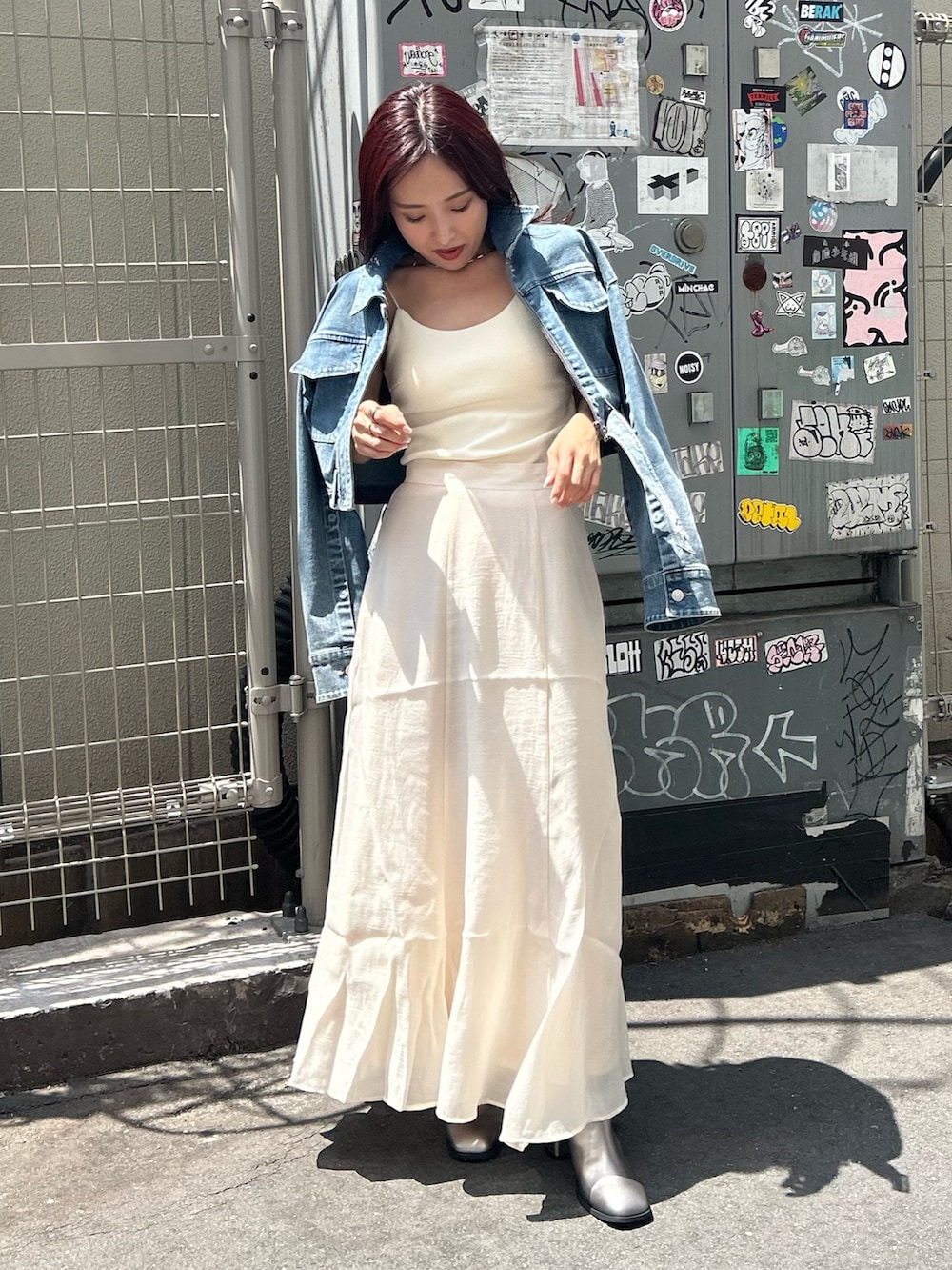 ホワイト系のスカート、ブルー系のデニムジャケット、ブラウン系のブーツを着用したレディースの夏コーディネートの3枚目の写真