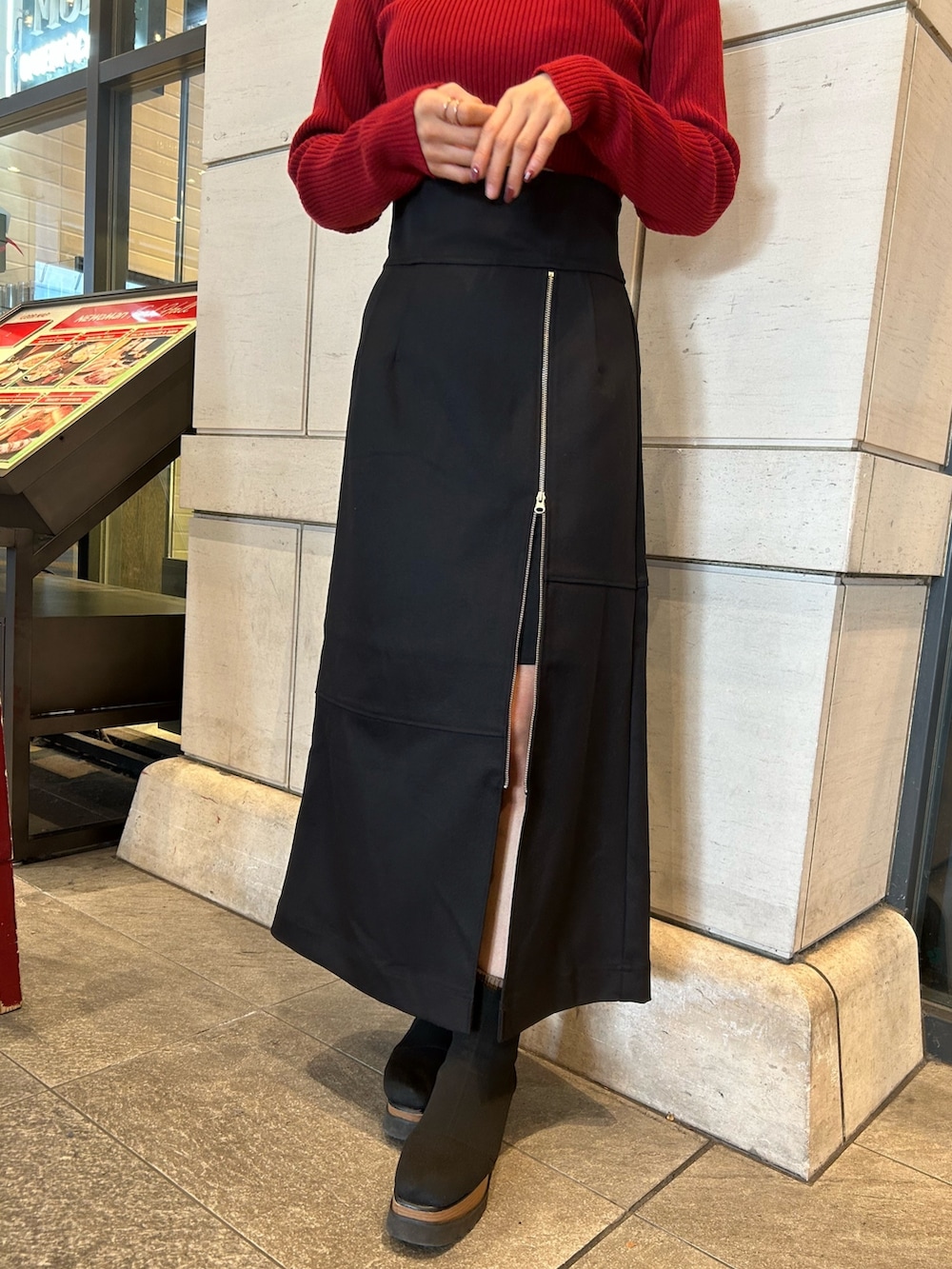 ブラック系のスカート、レッド系のニット/セーターを着用したレディースの秋コーディネートの3枚目の写真