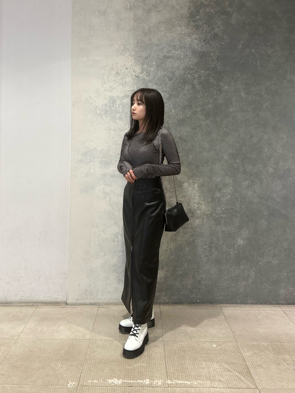 グレー系のTシャツ/カットソー、ブラック系のスカート、ブラック系のハンドバッグを着用したレディースの冬コーディネートの3枚目の写真