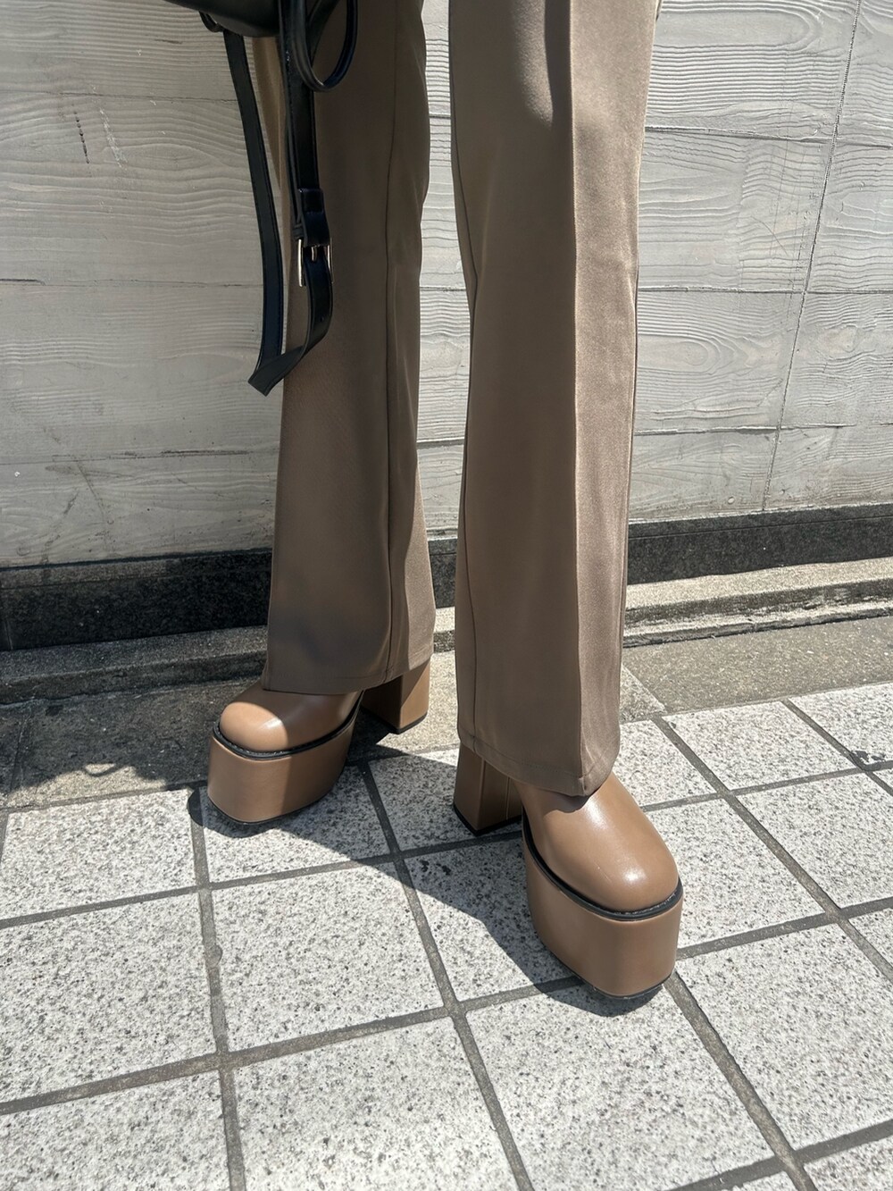 ブラウン系のブーツ、ブラウン系のスラックス、ブラック系のハンドバッグを着用したレディースの夏コーディネートの4枚目の写真