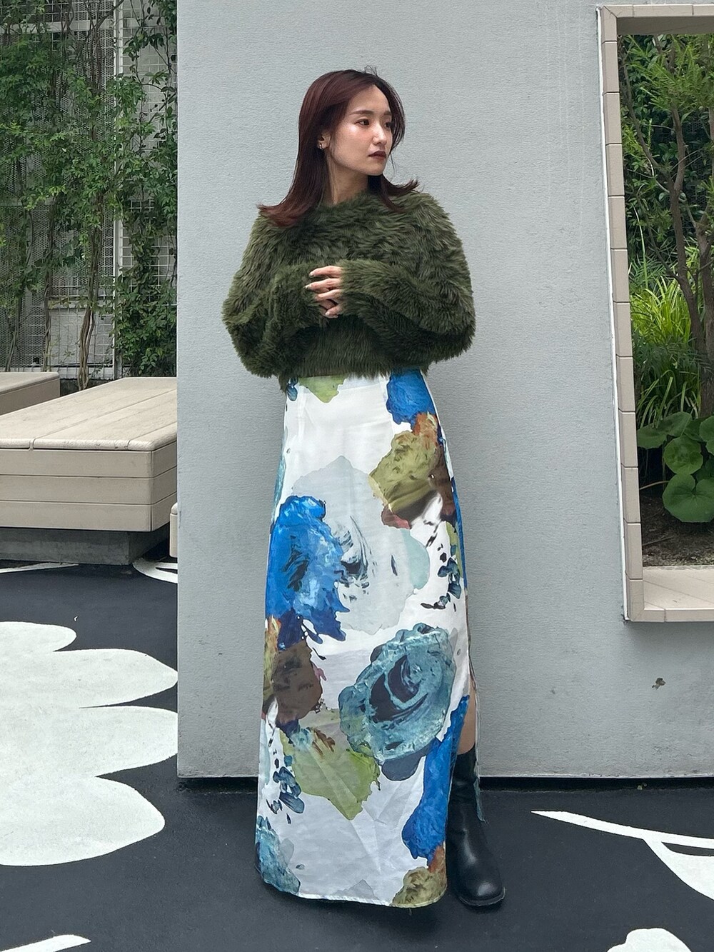 グリーン系のニット/セーター、ホワイト系のスカート、ブラック系のブーツを着用したレディースの夏コーディネートの2枚目の写真