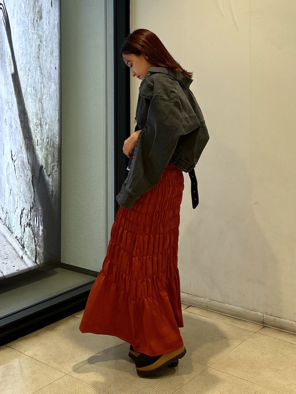 ブラック系のデニムジャケット、ホワイト系のTシャツ/カットソー、オレンジ系のスカートを着用したレディースの夏コーディネートの2枚目の写真