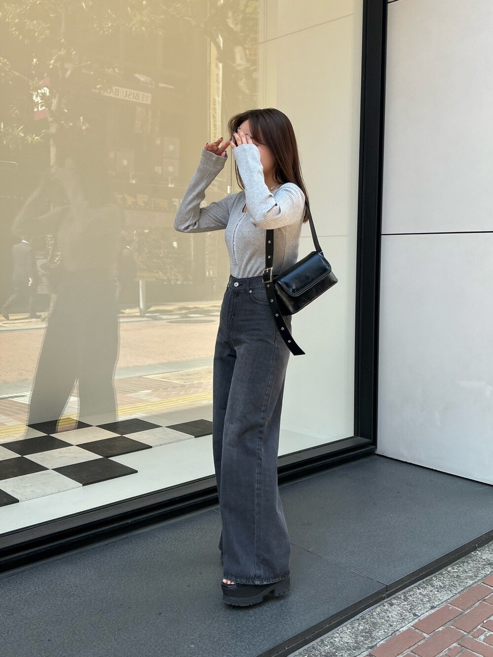 グレー系のTシャツ/カットソー、ブラック系のデニムパンツ、ブラック系のショルダーバッグを着用したレディースの春コーディネートの2枚目の写真
