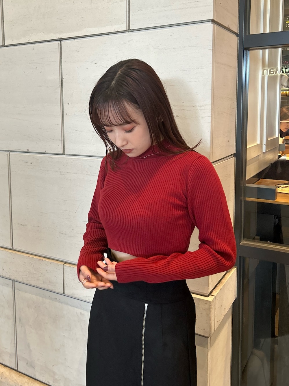 ブラック系のスカート、レッド系のニット/セーターを着用したレディースの秋コーディネートの2枚目の写真