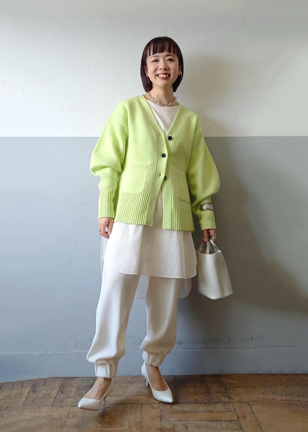 ホワイト系のショルダーバッグ、グリーン系のカーディガン/ボレロ、ホワイト系のパンプスを着用したレディースの秋コーディネートの2枚目の写真