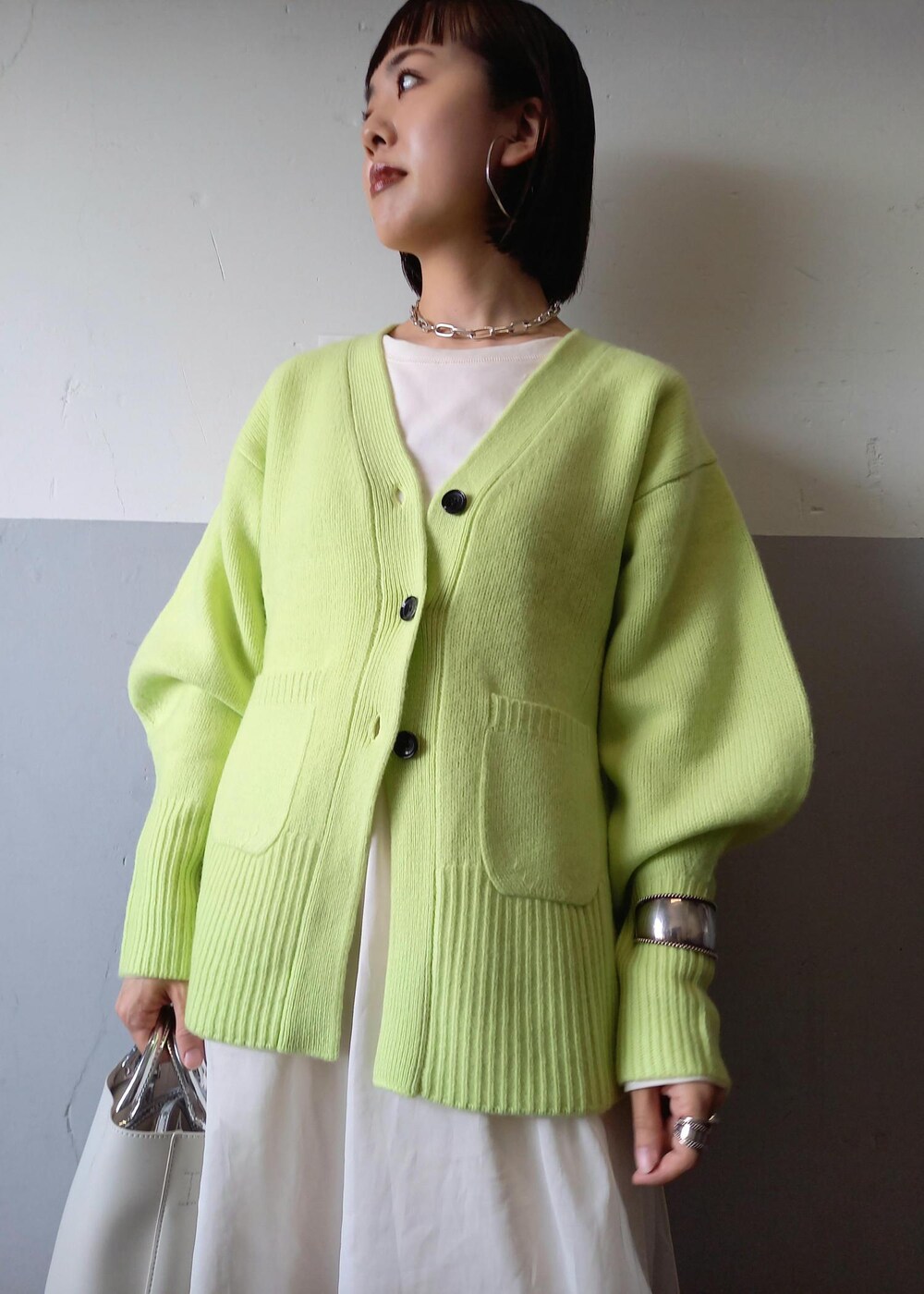 ホワイト系のショルダーバッグ、グリーン系のカーディガン/ボレロ、ホワイト系のパンプスを着用したレディースの秋コーディネートの7枚目の写真