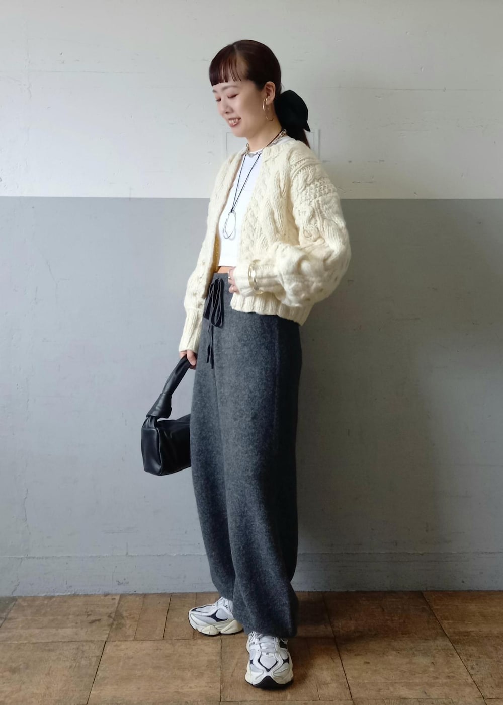 ブラック系のハンドバッグ、ホワイト系のカーディガン/ボレロ、グレー系のその他パンツを着用したレディースの秋コーディネートの6枚目の写真