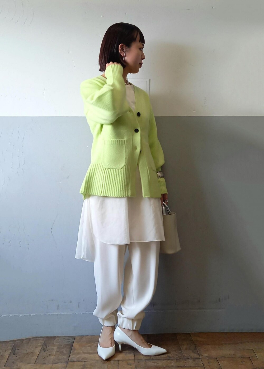 ホワイト系のショルダーバッグ、グリーン系のカーディガン/ボレロ、ホワイト系のパンプスを着用したレディースの秋コーディネートの3枚目の写真