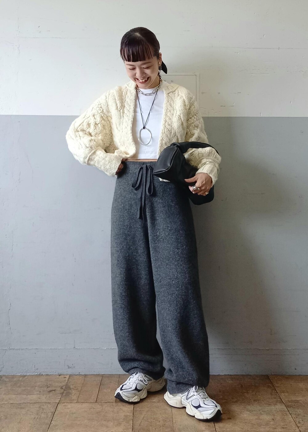 ブラック系のハンドバッグ、ホワイト系のカーディガン/ボレロ、グレー系のその他パンツを着用したレディースの秋コーディネートの2枚目の写真