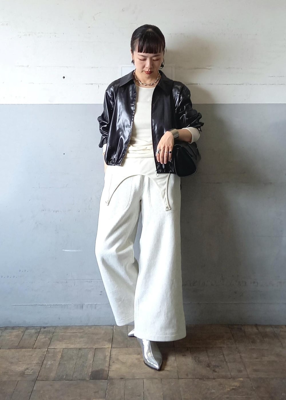 ブラック系のブルゾン、ホワイト系のTシャツ/カットソー、ブラック系のショルダーバッグを着用したレディースの秋コーディネートの2枚目の写真