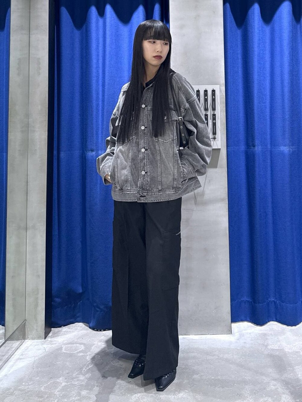 ブラック系のハンドバッグ、ブラック系のブルゾン、ブラック系のスラックスを着用したレディースの冬コーディネートの3枚目の写真