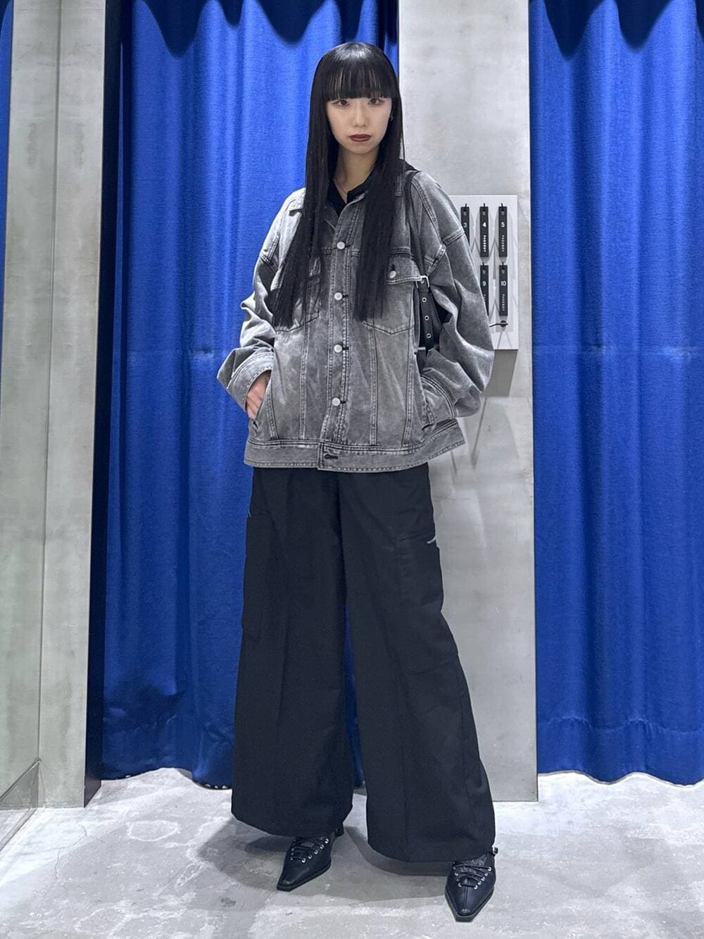 ブラック系のハンドバッグ、ブラック系のブルゾン、ブラック系のスラックスを着用したレディースの冬コーディネートの2枚目の写真