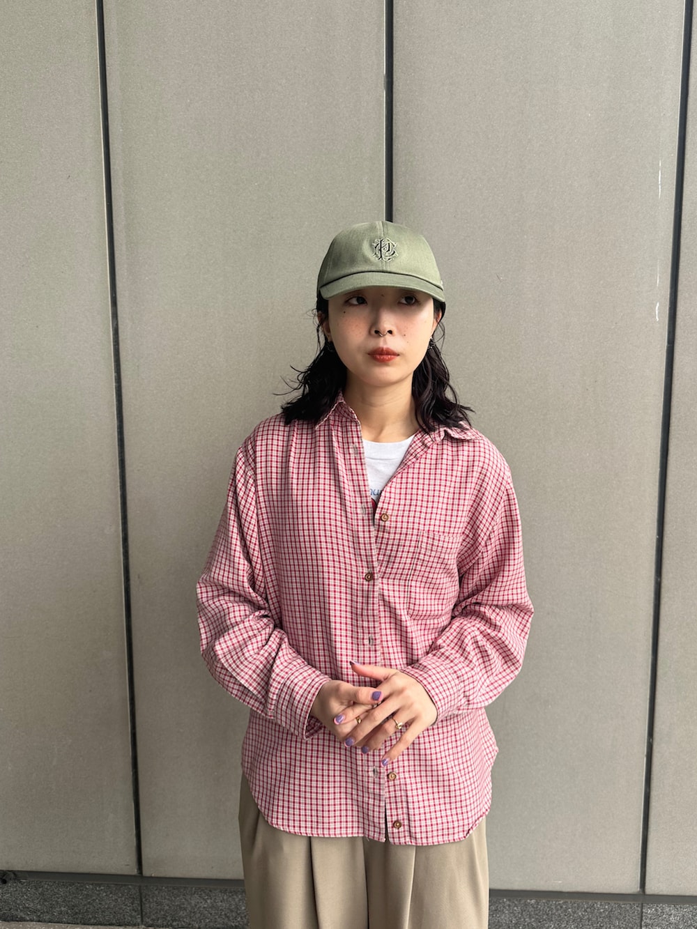 ベージュ系のスラックス、レッド系のシューズ、グリーン系のキャップを着用したレディースの春コーディネートの2枚目の写真