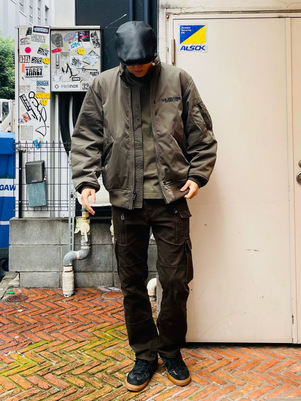 グリーン系のMA-1、ブラウン系のカーゴパンツ、ブラック系のスニーカーを着用したメンズの秋コーディネートの2枚目の写真