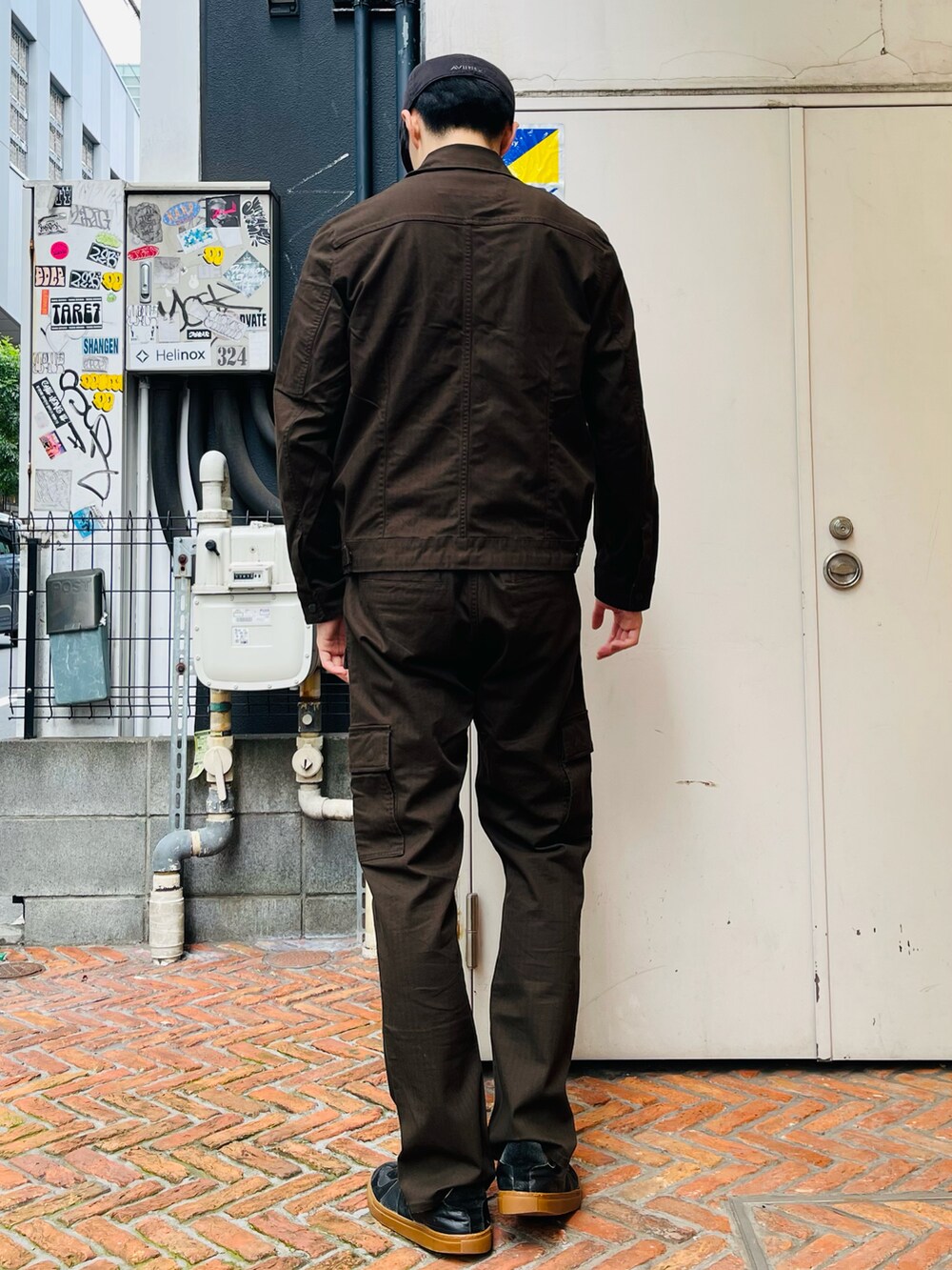 グリーン系のミリタリージャケット、ブラウン系のカーゴパンツ、ホワイト系のTシャツ/カットソーを着用したメンズの夏コーディネートの2枚目の写真